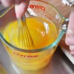 Someone whisking eggs in a Pyrex measure glass.