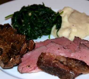 A plate of sous vide mustard and herb seasoned butterflied lamb leg with garlic cauliflower mash and spinach.