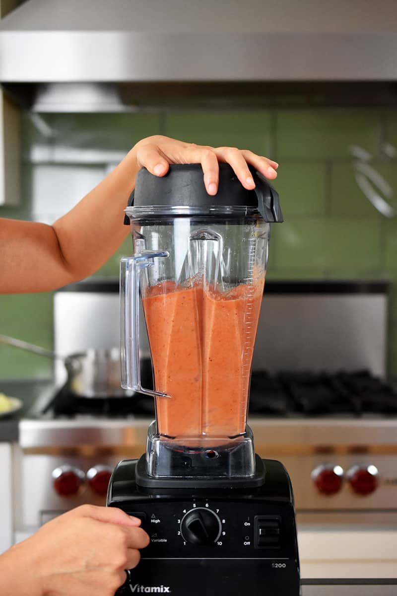 A Vitamix blender blending diced canned tomatoes into a puree