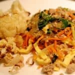 A plate with roasted cauliflower and paleo and whole30 stir fried kelp noodles with pork, eggs, and broccoli slaw.
