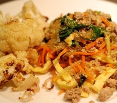 A plate with roasted cauliflower and paleo and whole30 stir fried kelp noodles with pork, eggs, and broccoli slaw.