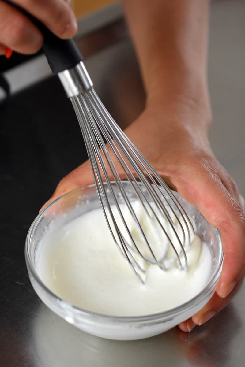 Whisking mayonnaise and lemon juice in a small bowl to make a dressing for crab salad.