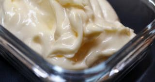 A closeup of thick and creamy paleo mayonnaise in a glass container.