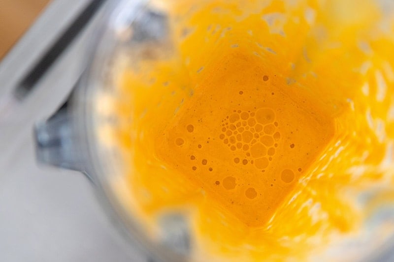 An overhead shot of the tangy carrot and ginger dressing in an open Vitamix blender.