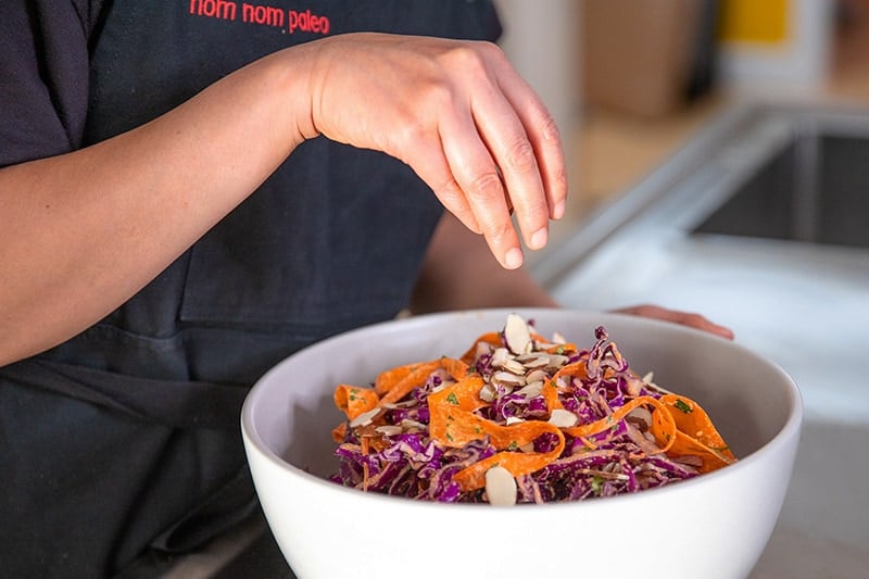 Adding toasted almonds on top of Whole30 and paleo red cabbage slaw.