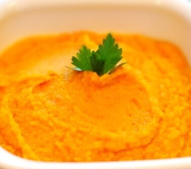 A white bowl containing carrot and parsnip puree.