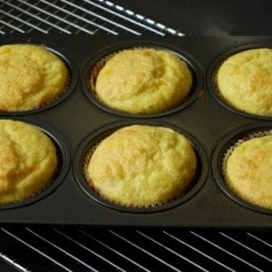 Six cheesy muffins in a muffin tin.
