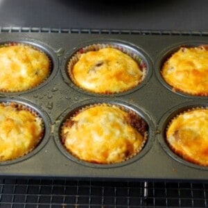 A tray of six mini frittata muffins with cheese and bacon.