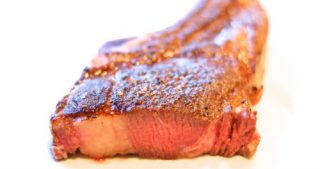 A sous vide grass fed rib steak or cowboy steak on a plate.