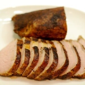 A plate of pork loin roast cooked sous vide sliced thin and presented on a white plate.
