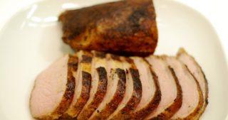A plate of pork loin roast cooked sous vide sliced thin and presented on a white plate.
