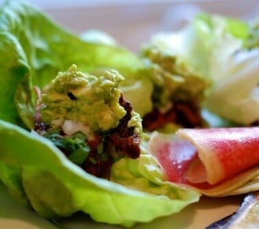 Carnitas cooked sous vide wrapped in lettuce and topped with guacamole.