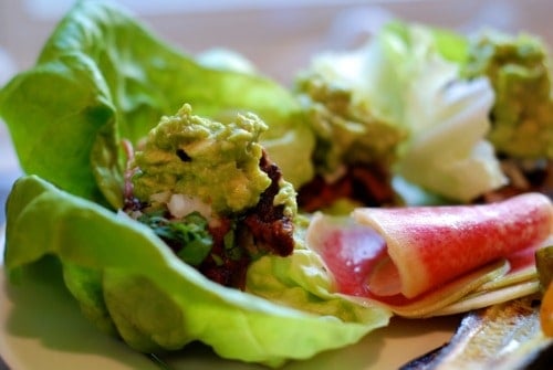 Carnitas cooked sous vide wrapped in lettuce and topped with guacamole.