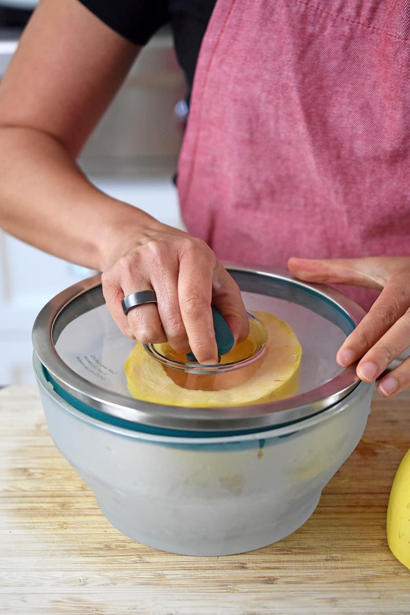 Placing a lid on a glass container with half a spaghetti squash inside.