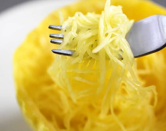 An overhead shot of a fork scooping up microwave spaghetti squash from a cut half.