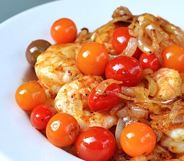 A plate of sautéed shrimp with roasted tomatoes and onions.