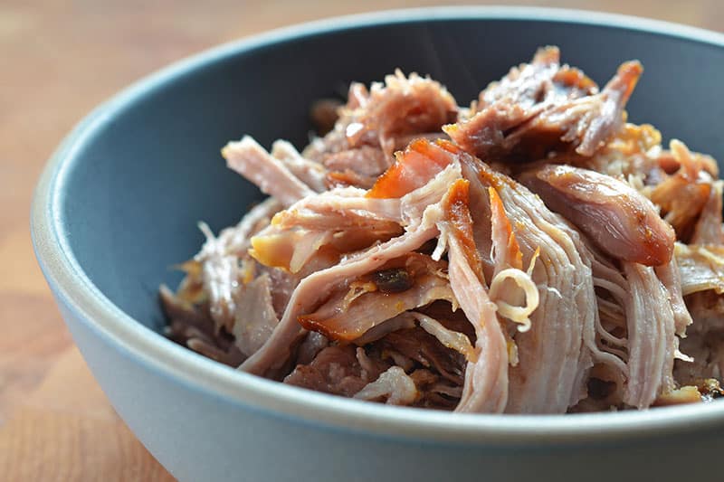 A closeup of shredded Slow Cooker Kalua Pig in a blue bowl