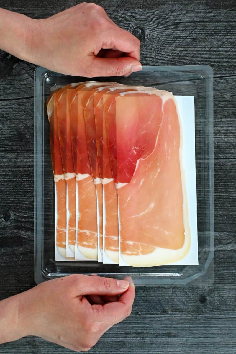 An overhead shot of an open tray of a package of pre-sliced prosciutto di Parma
