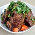 Beef short ribs topped with parsley in a bowl.