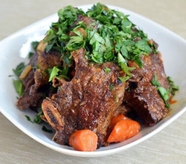 Beef short ribs topped with parsley in a bowl.