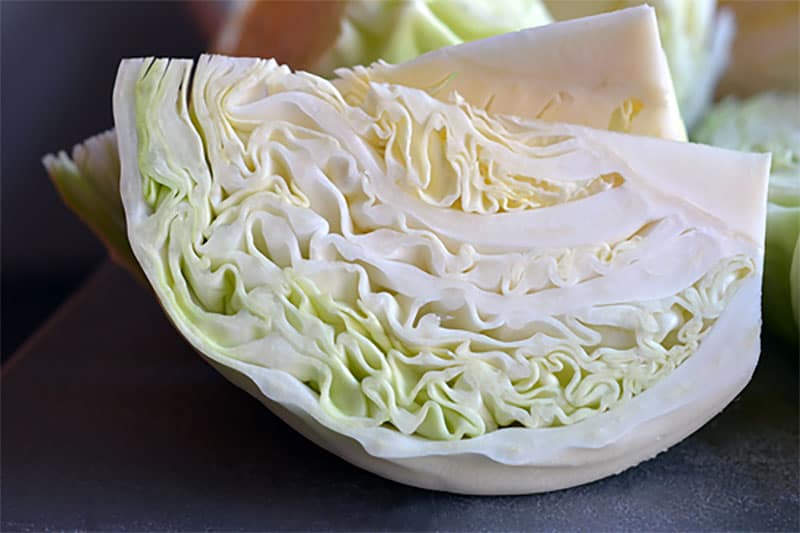 A closeup shot of cabbage wedges that will be added to Slow Cooker Cheater Pork Stew 