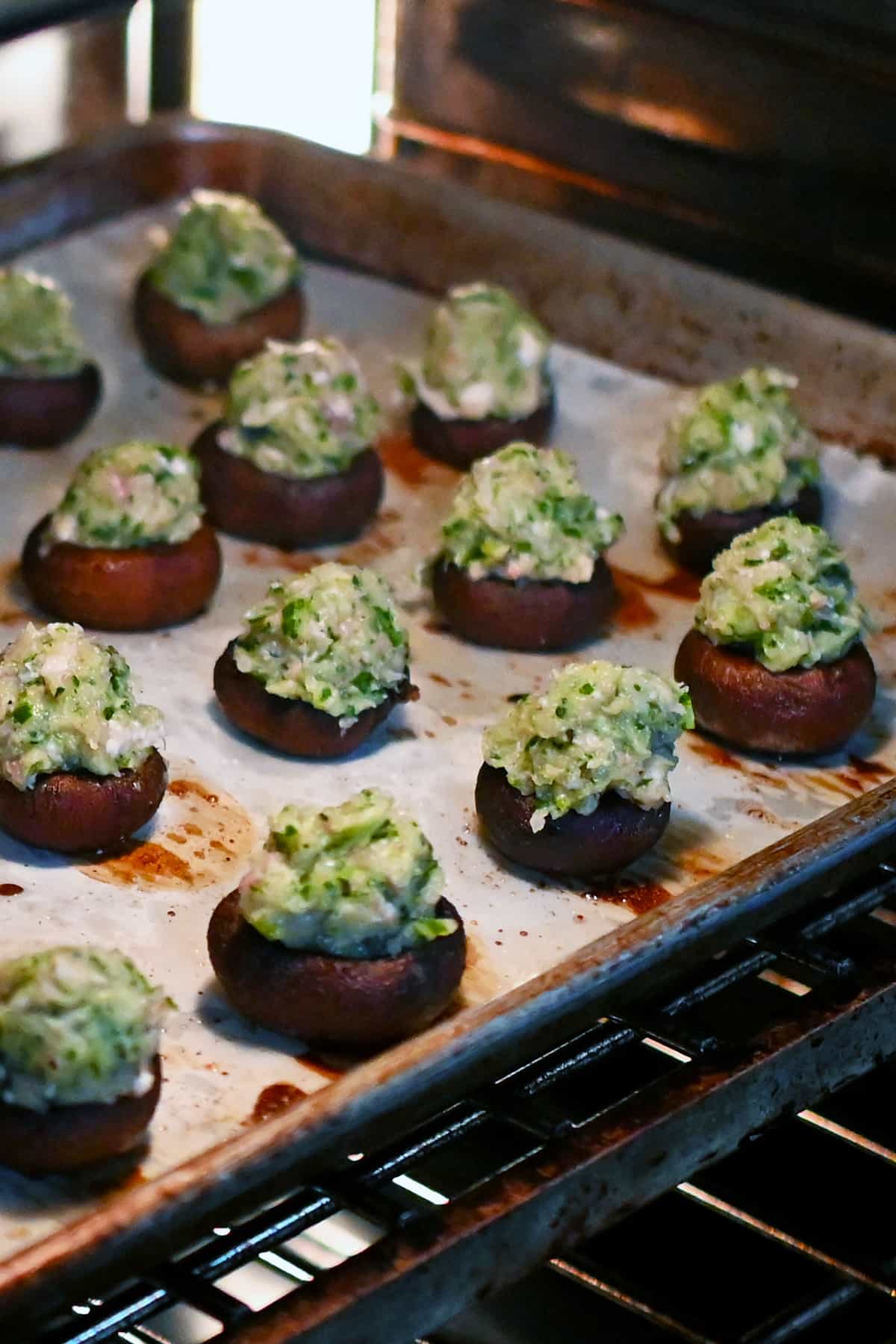 A tray of shrimp stuffed mushrooms being placed in the oven.