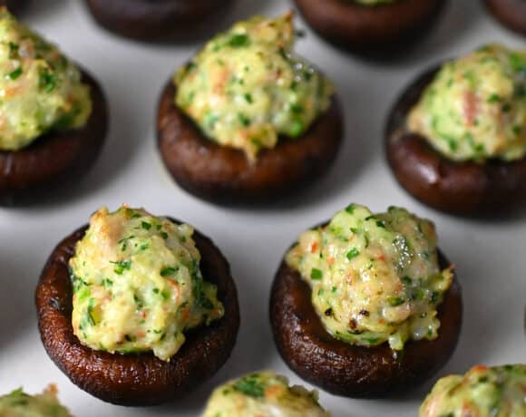 A closeup of freshly baked Chinese-inspired shrimp stuffed mushrooms on a parchment lined baking tray.
