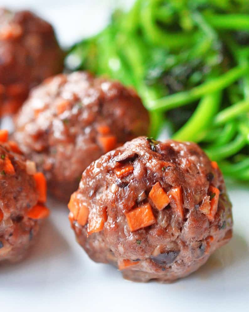 A close up shot of Asian Meatballs and a pile of stir-fried greens.