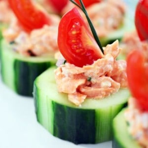 Spicy salmon on top of sliced cucumbers topped with cherry tomatoes.
