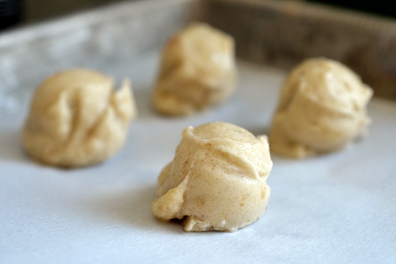 Closeup of the paleo banana ice cream scoops on a parchment lined baking sheet.