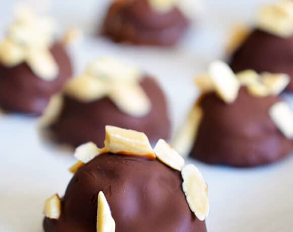 A closeup of a tray of Chunky Monkey Ice Cream Bon Bons, a paleo and vegan dessert with banana ice cream topped with a chocolate shell and toasted almonds.