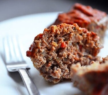 A plate with a paleo meatloaf muffin cut in half.