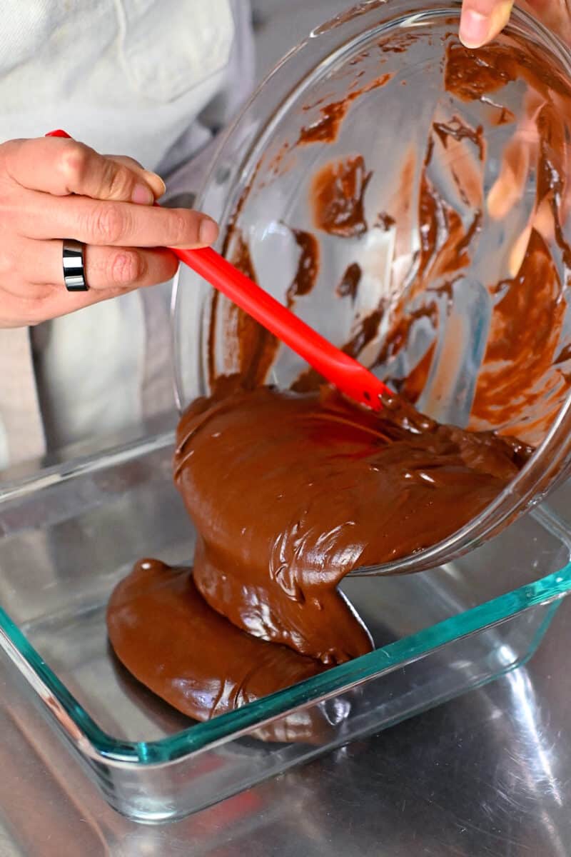 Pouring the paleo and vegan ganache into a glass storage container before chilling.