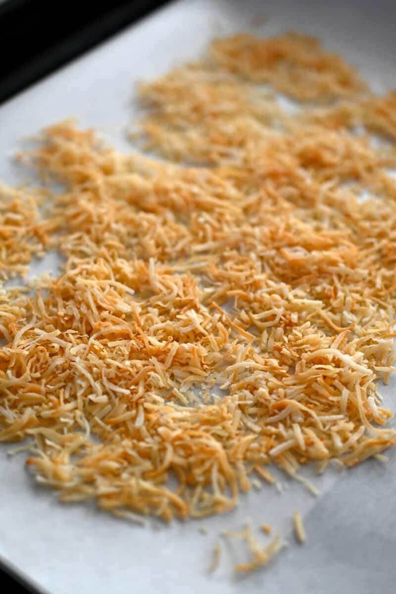 A closeup of the toasted shredded coconut on a rimmed baking sheet.