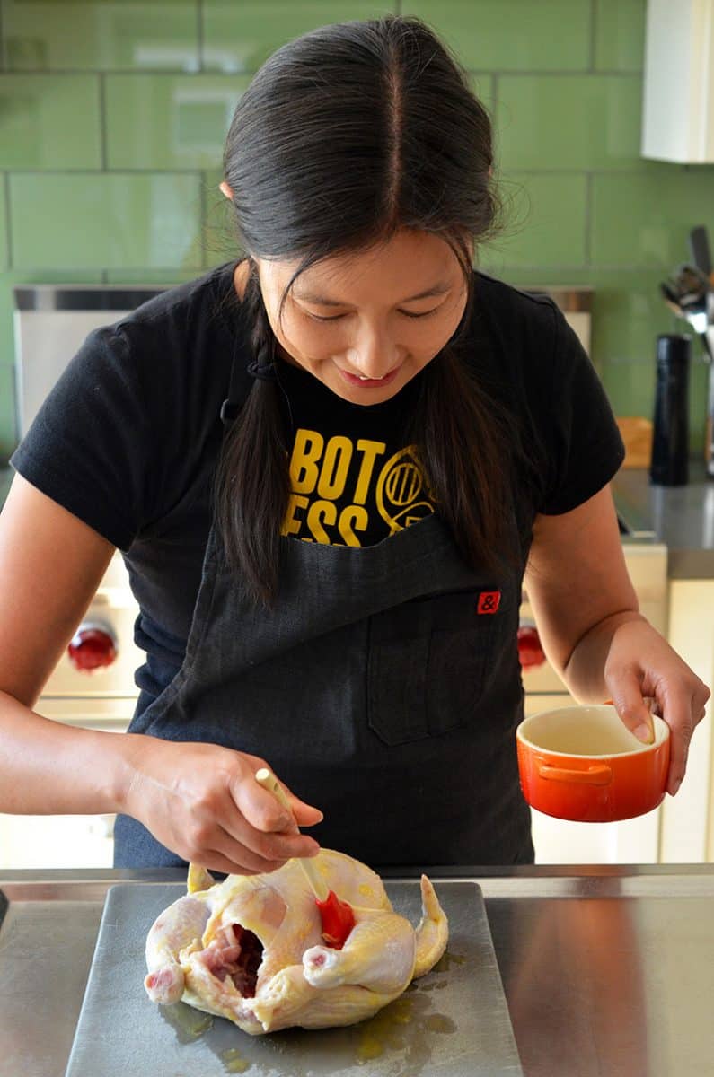 Michelle Tam brushing melted ghee on a raw whole chicken to make paleo roast chicken