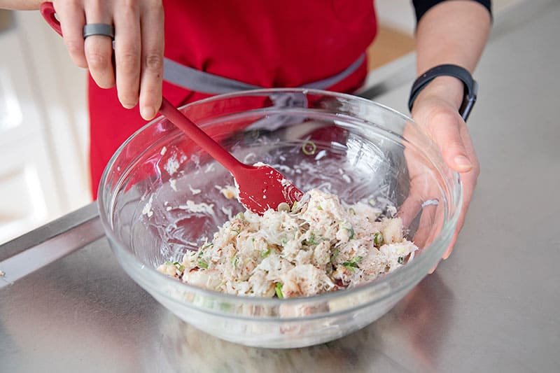 Someone using a red silicone spatula to mix up the filling for gluten-free and low carb California sushi hand rolls.