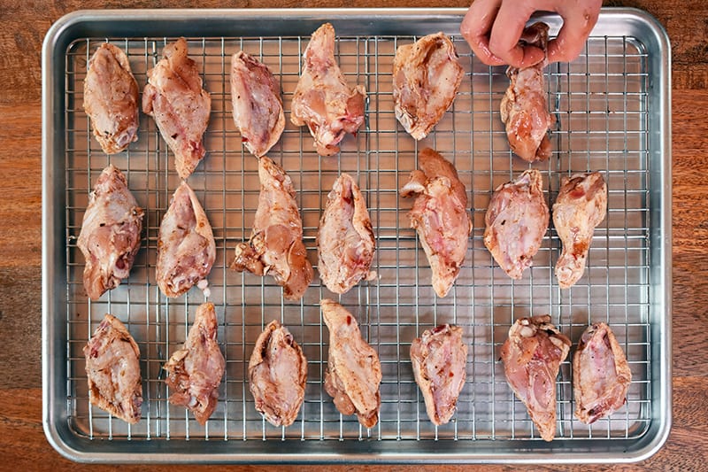 Arranged chicken wings in rows on a wire rack, ready to cook.