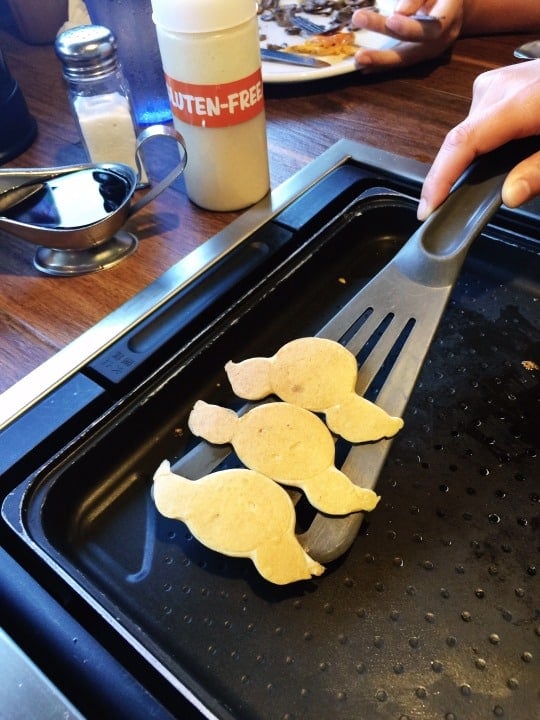 A spatula is picking up gluten-free pancakes from the griddle at Slappy Cakes in Maui