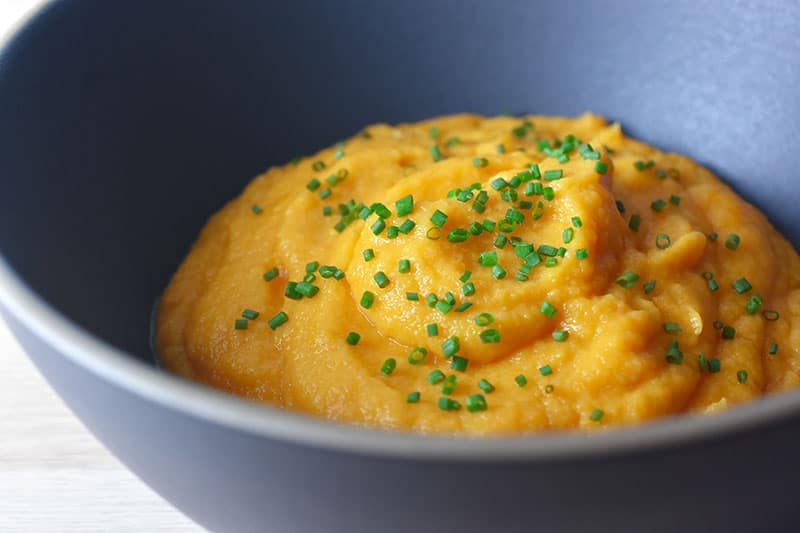 A closeup shot of Instant Pot Autumn Mash in a blue bowl topped with chopped chives