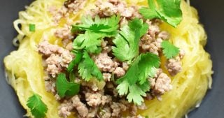 An overhead shot of a bowl of Instant Pot spaghetti squash topped with stir-fried ground pork and cilantro leaves.