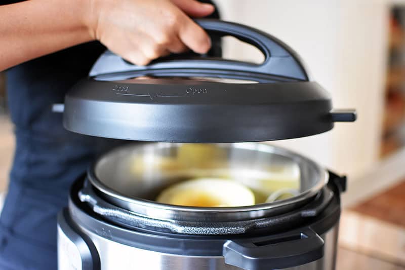 A close-up of an Instant Pot lid being lowered to cover the spaghetti squash.