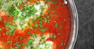 An overhead shot of Poached Cod in Tomato Sauce in a large stainless steel skillet.