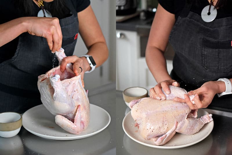 A woman seasoning a whole chicken with kosher salt.