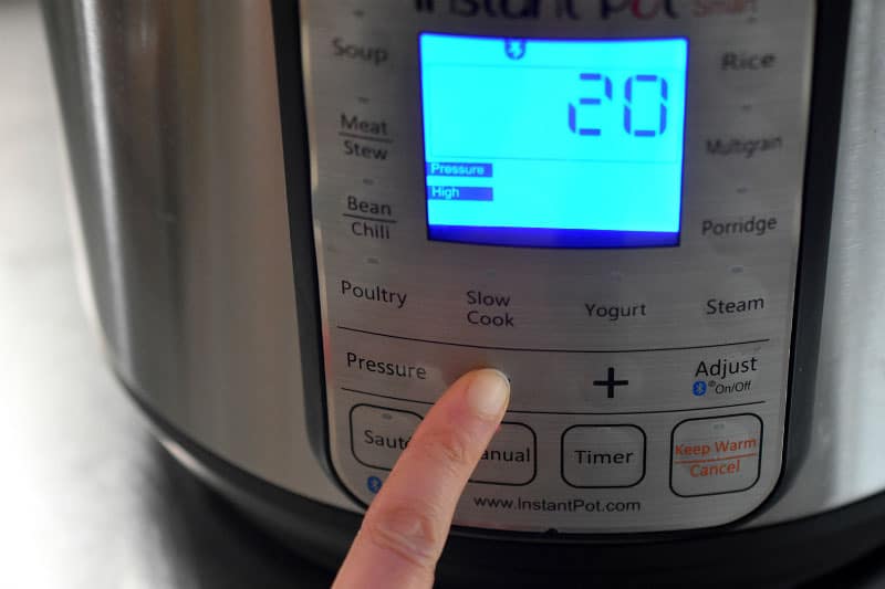 An Instant Pot display shows that it is programmed to cook for 20 minutes under high pressure.