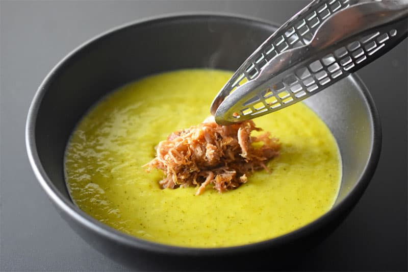 A closeup of a bowl of Instant Pot Curried Cream of Broccoli Soup topped with some crispy Kalua Pig