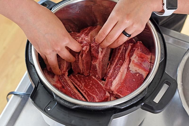 An overhead shot of rearranging short ribs into the Instant Pot.