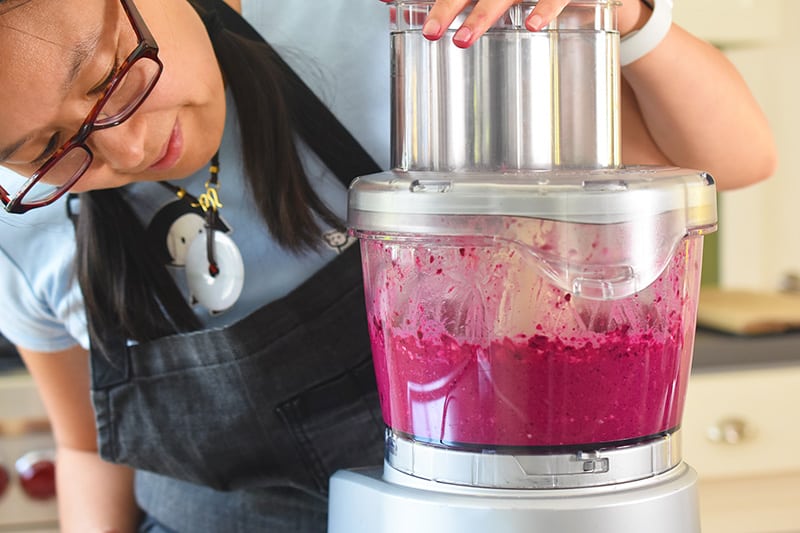 Someone mixing beets in a food processor.