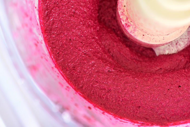 Close up of the ingredients for beet hummus blended together in a food processor.