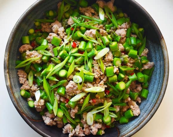 An overhead shot of Spicy Pork and Asparagus Stir-Fry in a blue serving bowl.
