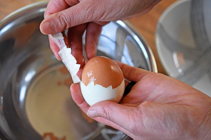 Someone peeling a hard cooked egg.